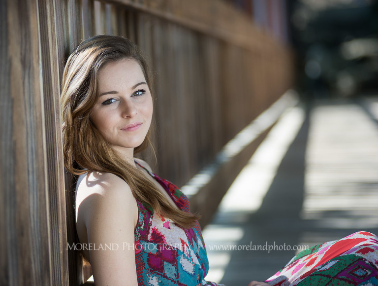 mikemoreland, morelandphoto, edgy, outdoors, medium close-up, soft lighting, slight smile, colorful dress, sitting on bridge