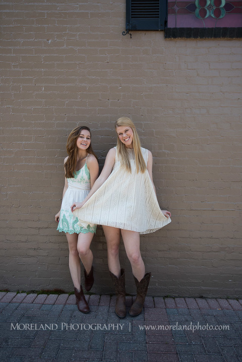 mikemoreland, morelandphoto, graduating sisters, family, college graduation, high school graduation, fun, outdoors, long shot, soft lighting, big smile, white dresses with boots, against a wall