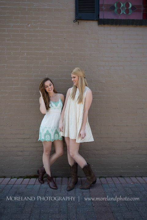 mikemoreland, morelandphoto, graduating sisters, family, college graduation, high school graduation, fun, outdoors, long shot, soft lighting, big smile, white dresses with boots, against a wall