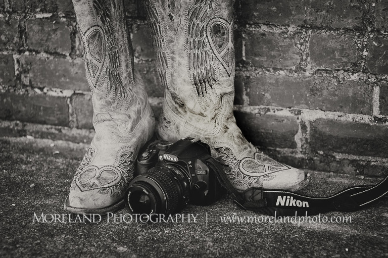 Close up of cowgirl boots and a camera in front of them, Roswell Senior Photography, Atlanta Senior Portraits, Senior Photography, Atlanta Senior Photography, Moreland Photography, Mike Moreland, Class of 2016, mikemoreland, morelandphoto, excitement, class of 2016, country girl, sparkling future, big grin, posing by wall, cowgirl boots, medium close up portrait, camera lies gently