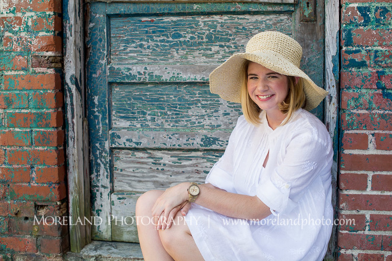 High school senior sitting by an old door with a hat on, Roswell Senior Photography, Atlanta Senior Portraits, Senior Photography, Atlanta Senior Photography, Moreland Photography, Mike Moreland, Class of 2016, mikemoreland, morelandphoto, excitement, class of 2016, country girl, sparkling future, big grin, posing by door, white blouse, sitting portrait, strawhat