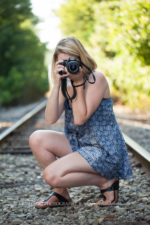 High school senior crouching down and taking pictures on abandoned railroad tracks, Roswell Senior Photography, Atlanta Senior Portraits, Senior Photography, Atlanta Senior Photography, Moreland Photography, Mike Moreland, Class of 2016, mikemoreland, morelandphoto, excitement, class of 2016, country girl, sparkling future, big grin, posing by train tracks, mixed color blouse, model portrait, afternoon, black and white photography, having fun, playing on the railroad, taking photos