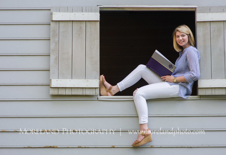 High school senior sitting on the window opening of a barn holding her yearbook, Roswell Senior Photography, Atlanta Senior Portraits, Senior Photography, Atlanta Senior Photography, Moreland Photography, Mike Moreland, Class of 2016, mikemoreland, morelandphoto, excitement, class of 2016, country girl, sparkling future, big grin, classy and sassy, model portrait, afternoon, yearbook editor, having fun, hangin' out a barn door, reading