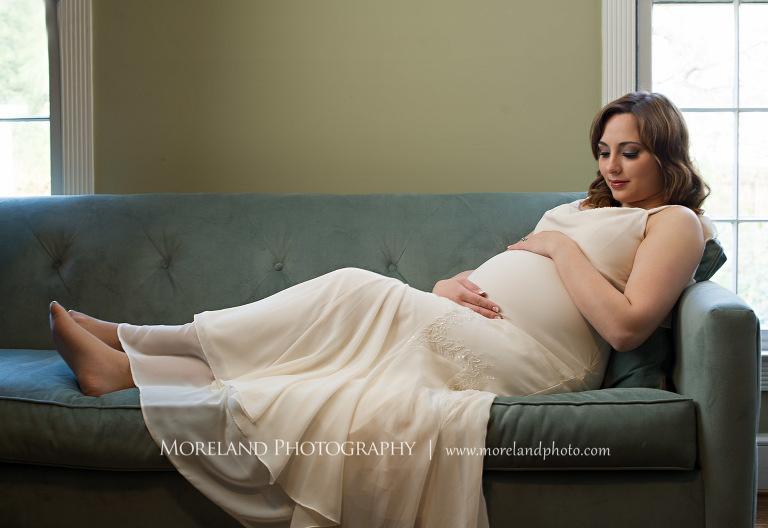 Pregnant woman looking at her stomach while she holds it as she sits on the couch with his feet up , beautiful, serene, love, joy, happiness, classic, timeless