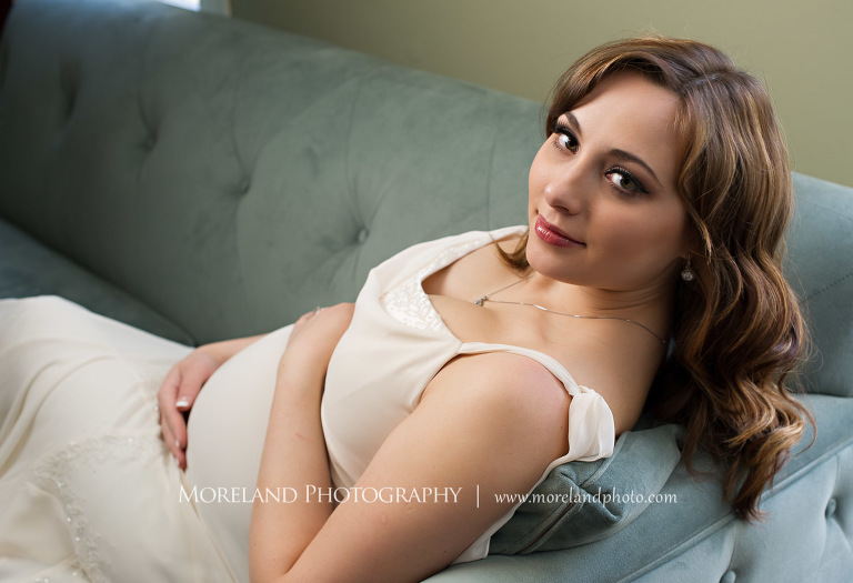 Pregnant woman looking up while she holds her stomach as she sits on the couch with his feet up , hollywood maternity, beautiful, serene, love, joy, happiness, classic, timeless