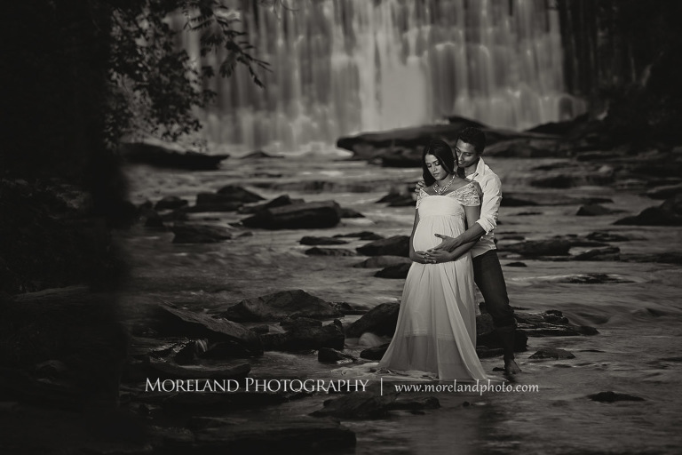 Gray scale image of Indian couple expecting their first baby standing by a waterfall, serene , tranquil, love, peaceful, joy, happiness, protection, natural, nature