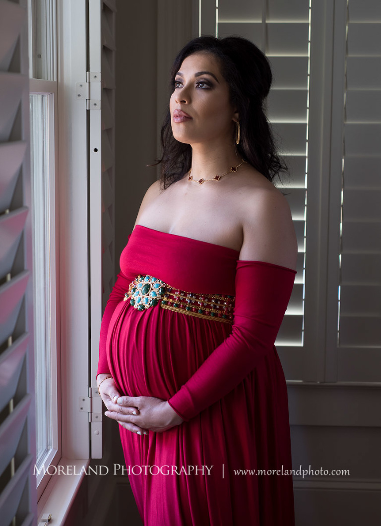 Regal pregnant woman in gorgeous red dress cradling pregnant belly gazing out of a window, pregnancy, romantic pregnancy photo shoot, red maternity dress, Atlanta area photography, Atlanta area maternity photographers, fashion maternity shoots, regal estates for photos, mike moreland photography 