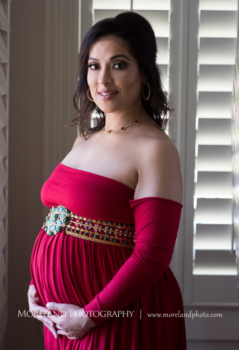 Regal pregnant woman in gorgeous red dress cradling pregnant belly faintly smiling at the camera, pregnancy, romantic pregnancy photo shoot, red maternity dress, Atlanta area photography, Atlanta area maternity photographers, fashion maternity shoots, regal estates for photos, mike moreland photography 