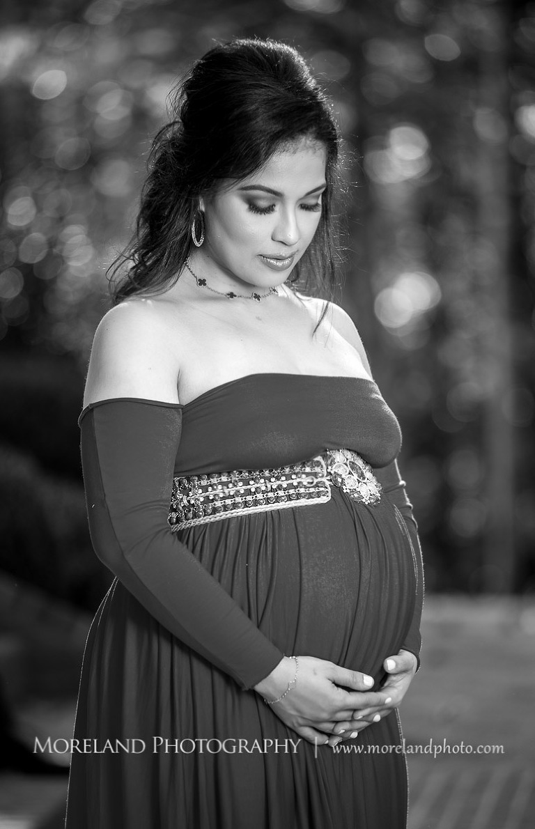 Gray scale image of elegant pregnant woman in sophisticated red maternity dress with eyes closed looking down while cradling belly outside, pregnancy, romantic pregnancy photo shoot, outdoor maternity photo shoot, red maternity dress, Atlanta area photography, Atlanta area maternity photographers, fashion maternity shoots, regal estates for photos, mike moreland photography 
