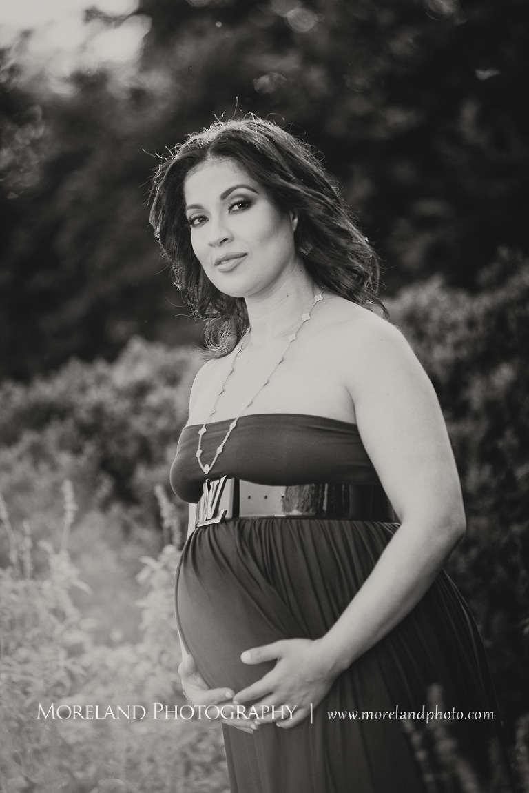 Gray scale fashion image of pregnant woman in purple maternity dress staring at camera while cradling belly outside, pregnancy, romantic pregnancy photo shoot, outdoor maternity photo shoot, purple maternity dress, Atlanta area photography, Atlanta area maternity photographers, fashion maternity shoots, regal estates for photos, mike moreland photography 