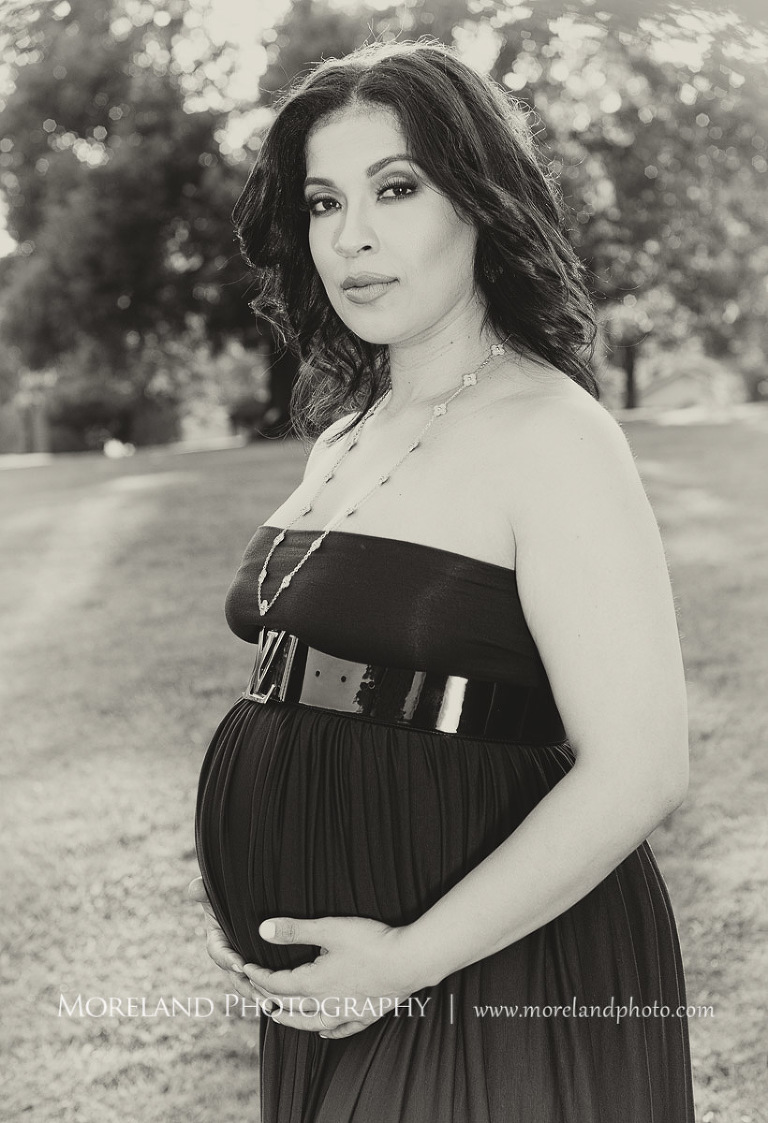 Gray scale image of pregnant woman holding belly staring at the camera in an open field outside, pregnancy, outdoor pregnancy photo shoots, maternity shoots with nature, purple maternity dress, romantic photo shoot, Atlanta area photography, Atlanta area maternity photographers, fashion maternity shoots, regal estates for photos, mike moreland photography 