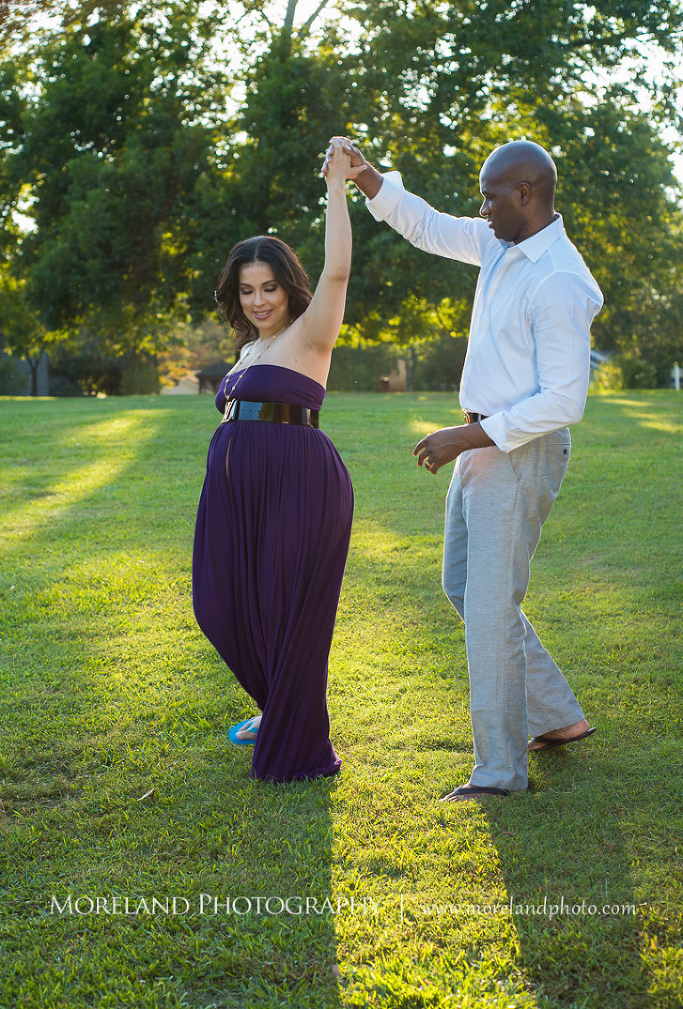 Interracial couple dancing in the middle of an open field outside, pregnancy, interracial couple, outdoor pregnancy photo shoots, maternity shoots with nature, fun maternity shoots, romantic pregnancy photo shoot, purple maternity dress, outdoor maternity photo shoot, romantic moment, romantic photo shoot, Atlanta area photography, Atlanta area maternity photographers, fashion maternity shoots, regal estates for photos, mike moreland photography 