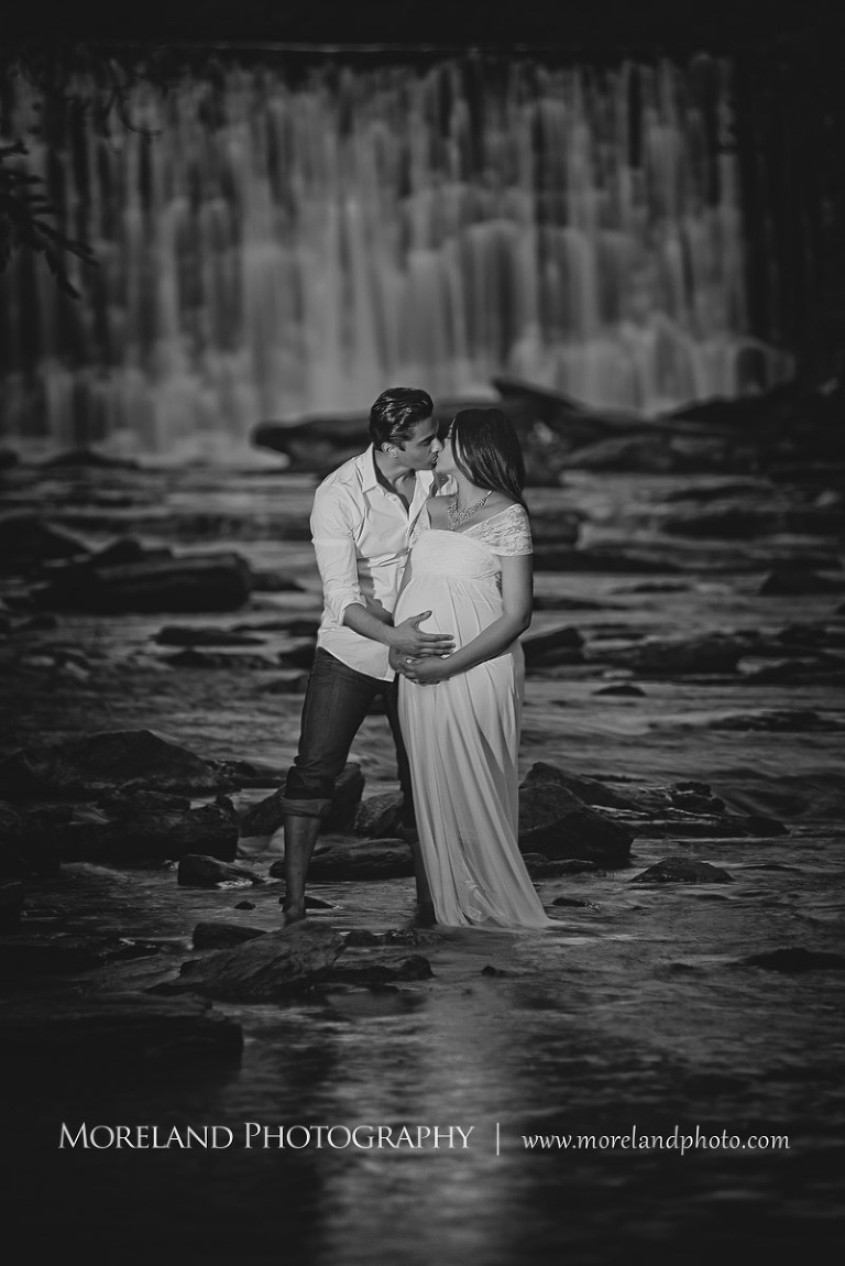 Gray scale of Indian husband kissing his pregnant indian wife by a waterfall, beautiful, love, adoration, nature, natural, joy, romance, peaceful, protection, serene