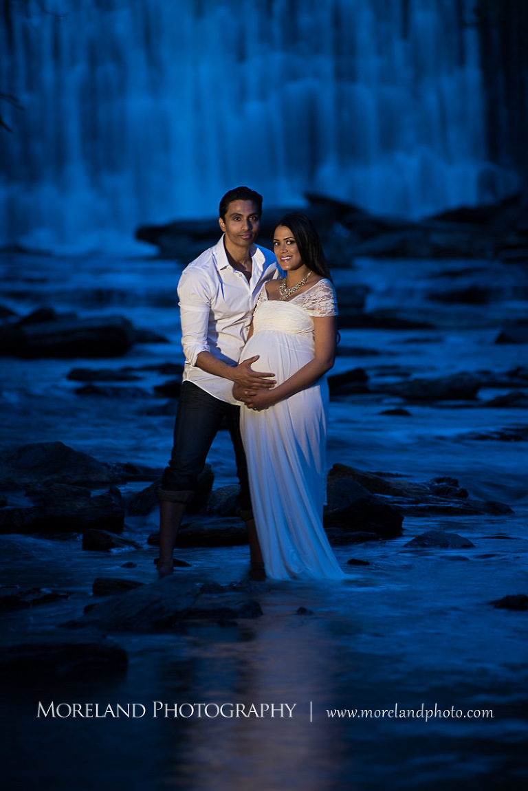 Indian husband touching his pregnant indian wife's stomach by a waterfall, beautiful, love, adoration, nature, natural, joy, romance, peaceful, protection, serene