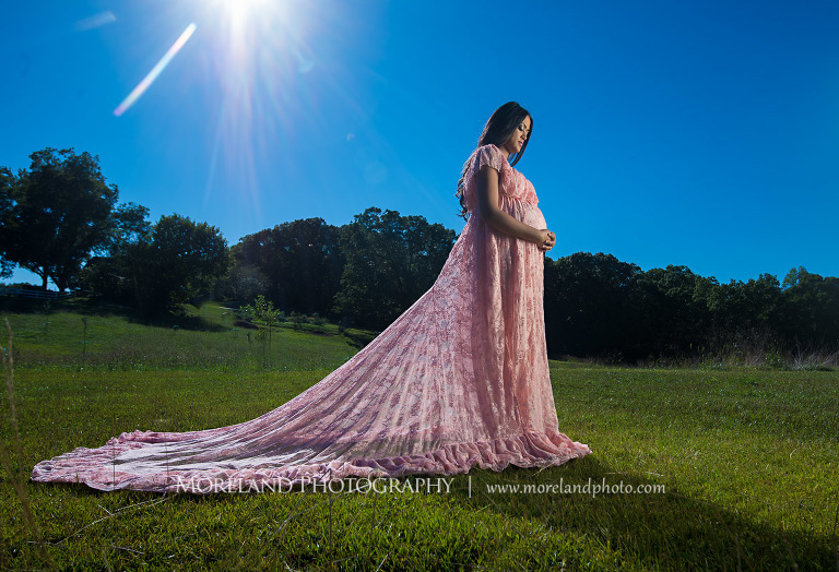 Indian woman holding her pregnant stomach on a field on a bright sunny day, love, peaceful, beautiful, joy, happiness, expecting
