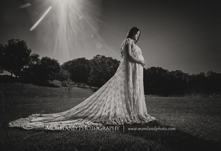 Gray scale image of Indian woman holding her pregnant stomach on a field on a bright sunny day, love, peaceful, beautiful, joy, happiness, expecting