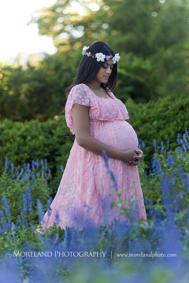Pregnant Indian woman holding her stomach in a flower garden, beautiful, love, adoration, nature, natural, joy, romance, peaceful, protection, serene