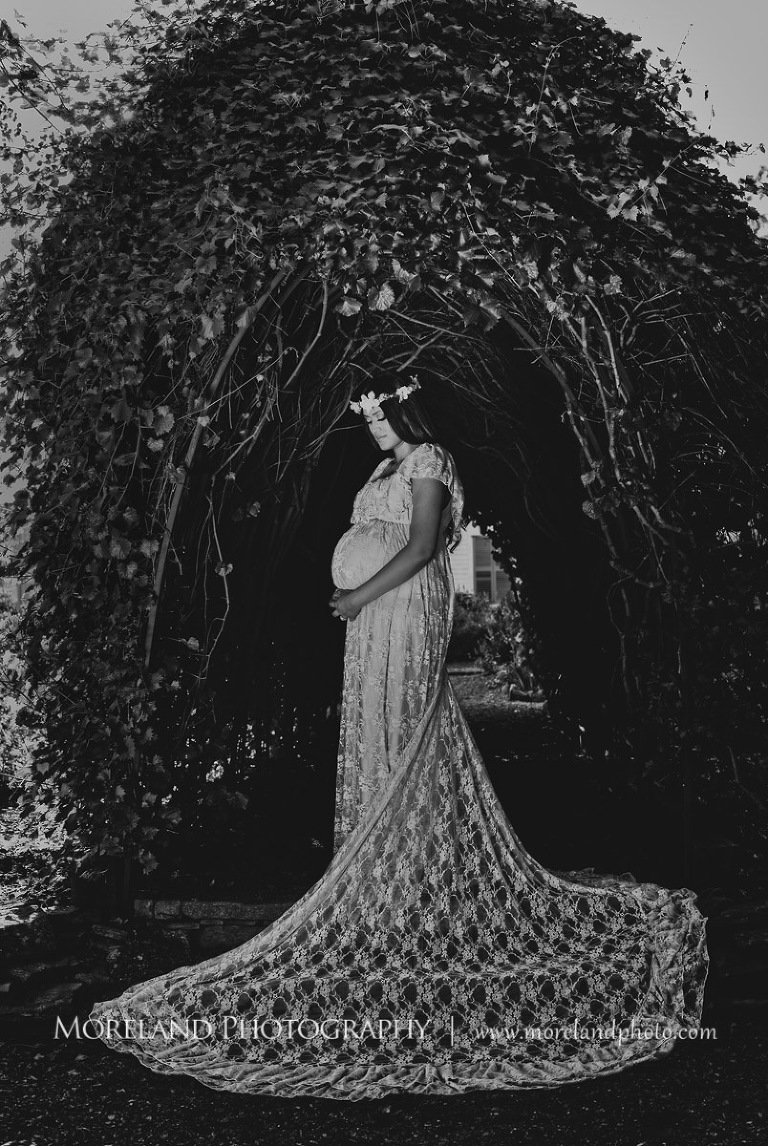 Gray scale of pregnant Indian woman holding her stomach under an archway, beautiful, love, adoration, nature, natural, joy, romance, peaceful, protection, serene