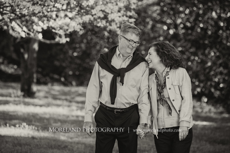 Black and white portait of a couple smiling and walking in front of a floral tree outside during the daytime, Atlanta Portrait Photographer, Atlanta Child Photographer, Atlanta Family Photographer, Moreland Photography, Mike Moreland