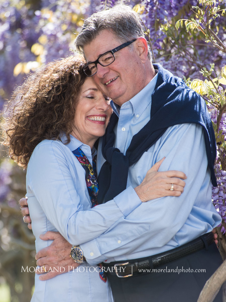 Portrait of couple wearing matching blue button down shirts smiling and holding each other outside in daytime in front of purple flowry bush, Family Moreland Photography, Atlanta Portrait Photographer, Atlanta Child Photographer, Atlanta Family Photographer, Moreland Photography, Mike Moreland