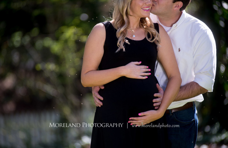 Husband holding his pregnant wife from behind as he kisses her on her cheek, Atlanta Maternity Photographer, Maternity Photos Atlanta, Georgia Maternity Photography, Moreland Photography, Mike Moreland, Outdoor Maternity, Maternity on the River, 