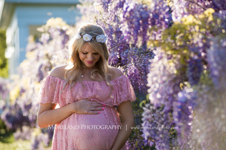 Pregnant woman looking down and touching her belly as she stands by purple flowers, Atlanta Maternity Photographer, Maternity Photos Atlanta, Georgia Maternity Photography, Moreland Photography, Mike Moreland, Outdoor Maternity, Maternity on the River, 
