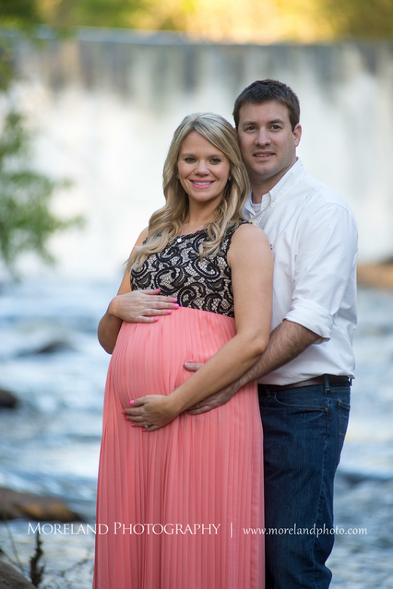 Husband holding his wife from behind with a waterfall in the background, Atlanta Maternity Photographer, Maternity Photos Atlanta, Georgia Maternity Photography, Moreland Photography, Mike Moreland, Outdoor Maternity, Maternity on the River, 