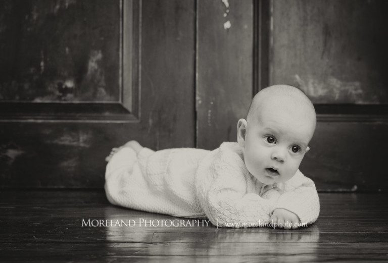 Gray scale of baby laying on the floor on their stomach wearing a onesie, Atlanta Family Photography, Family Photographer Atlanta, Atlanta Photographer, Moreland Photography, Mike Moreland, Four kids, Large family, Fall Family Pictures, 