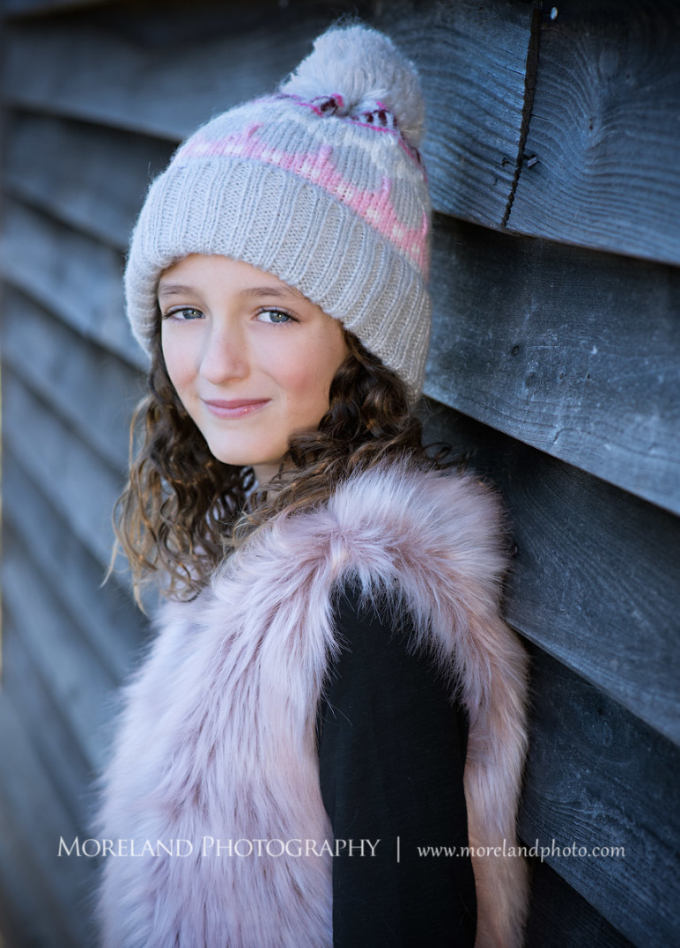 Portrait of little girl leaning against wooden wall in pink fury vest smiling at camera outside during daytime, Family Moments, Atlanta Portrait Photographer, Atlanta Child Photographer, Atlanta Family Photographer, Moreland Photography, Mike Moreland
