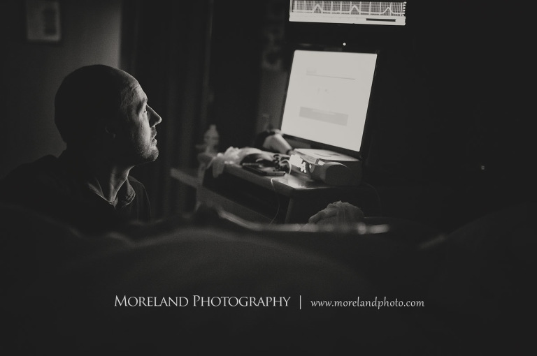 Grey-scale image of a father looking longily into the screen of his future child's heart monitor, birth photography, birth newborn photography, Atlanta Newborn Photography, Newborn Photographer Atlanta, Birth Photography, Natural Birth Photography, Hospital Photographer, Moreland Photography, Mike Moreland