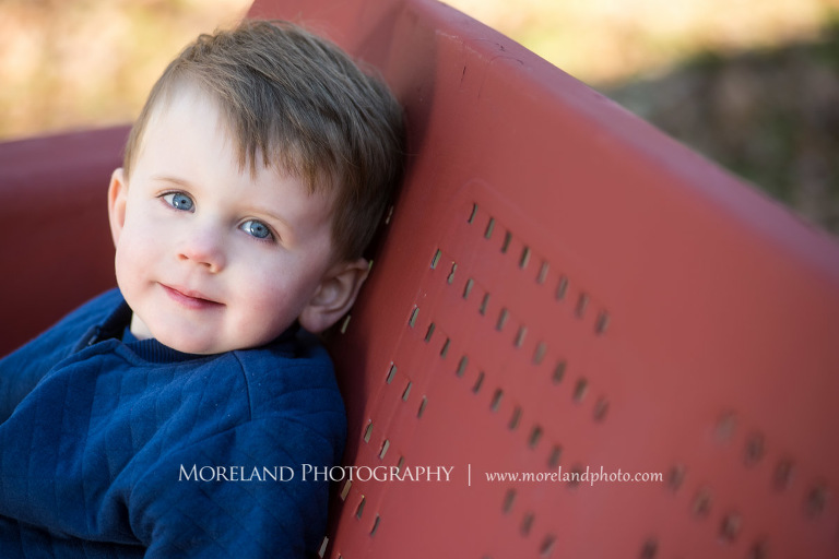 Medium close-up image of a young boy with bright blue eye staring at the camera while sitting on a red bench, Atlanta Newborn Photography, Newborn Photographer Atlanta, Birth Photography, Natural Birth Photography, Hospital Photographer, Moreland Photography, Mike Moreland
