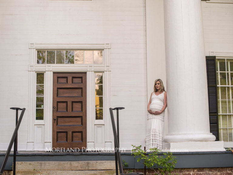 Portrait of pregnant woman holding her belly leaning against column standing in front of a white house, Maternity Photography, Atlanta Maternity, Lifestyle Maternity Photography, Styled Maternity Shoot, Moreland Photography, Mike Moreland, Outdoor Maternity, Nature Maternity, 