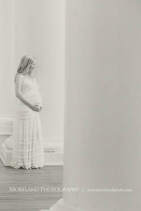 Black and white portrait of pregnant woman smiling and holding her belly leaning against column, Maternity Photography, Atlanta Maternity, Lifestyle Maternity Photography, Styled Maternity Shoot, Moreland Photography, Mike Moreland, Outdoor Maternity, Nature Maternity, 