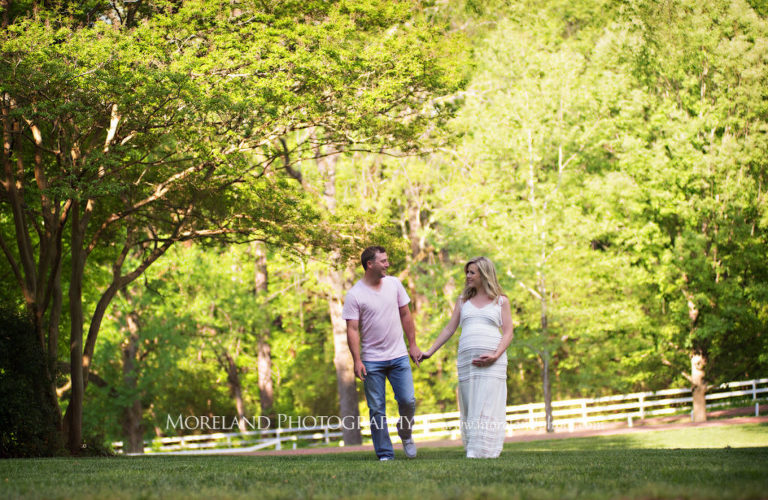 Portrait of pregnant couple smiling holding hands and walking outside during the daytime surrounded by trees, Maternity Photography, Atlanta Maternity, Lifestyle Maternity Photography, Styled Maternity Shoot, Moreland Photography, Mike Moreland, Outdoor Maternity, Nature Maternity, 