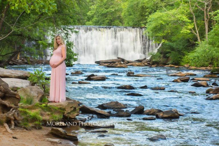 Portrait of pregnant woman in pink gain holding her belly standing on a rock in front of a waterfall, Maternity Photography, Atlanta Maternity, Lifestyle Maternity Photography, Styled Maternity Shoot, Moreland Photography, Mike Moreland, Outdoor Maternity, Nature Maternity, 