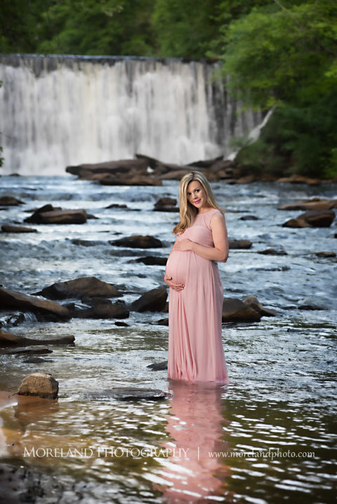 Portrait of pregnant woman in pink gown holding her belly standing in a river in front of a waterfall, Maternity Photography, Atlanta Maternity, Lifestyle Maternity Photography, Styled Maternity Shoot, Moreland Photography, Mike Moreland, Outdoor Maternity, Nature Maternity, 