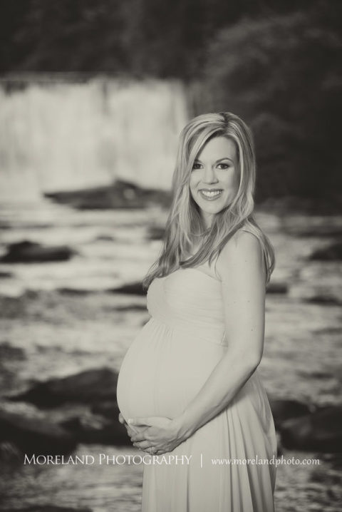 Black and white portrait of pregnant woman in pink gown smiling holding her belly standing in front of a waterfall, Maternity Photography, Atlanta Maternity, Lifestyle Maternity Photography, Styled Maternity Shoot, Moreland Photography, Mike Moreland, Outdoor Maternity, Nature Maternity, 