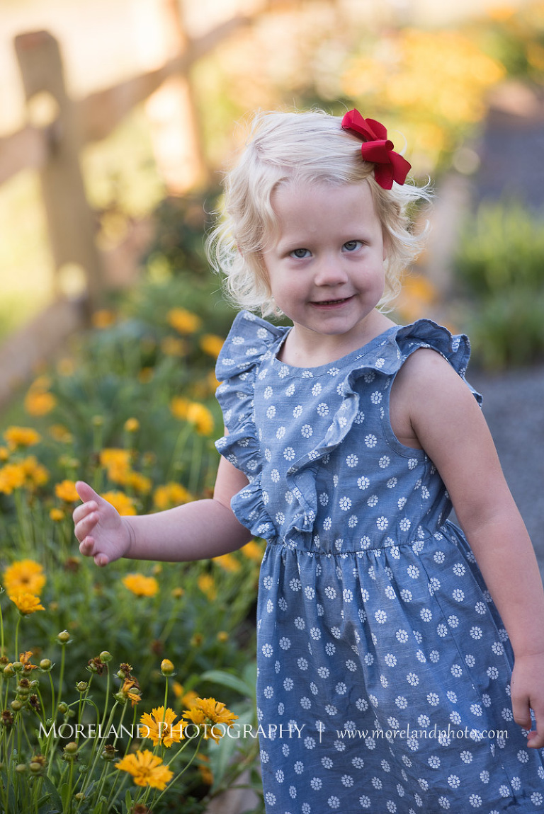 little girl in polka dot dress with red bow in garden, Mike Moreland, Moreland Photography, wedding photography, Atlanta wedding photography, detailed wedding photography, lifestyle wedding photography, Atlanta wedding photographer,