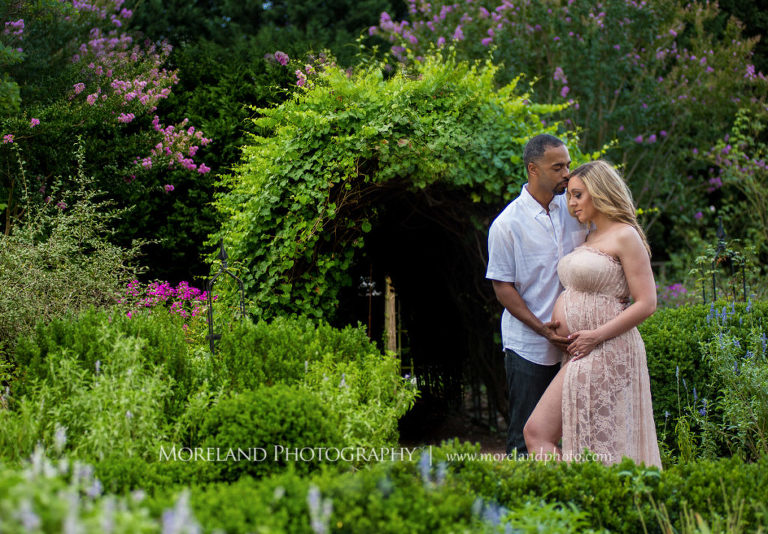 Pregnant woman and husband standing in English garden wearing pink, flowy maternity dress, Mike Moreland, Moreland Photography, Atlanta Portrait Photographer, Maternity Photography Atlanta