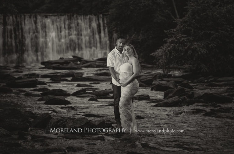 Black and white pregnant woman and husband standing in front of waterfall wearing white, lacey maternity dress, Mike Moreland, Moreland Photography, Atlanta Portrait Photographer, Maternity Photography Atlanta