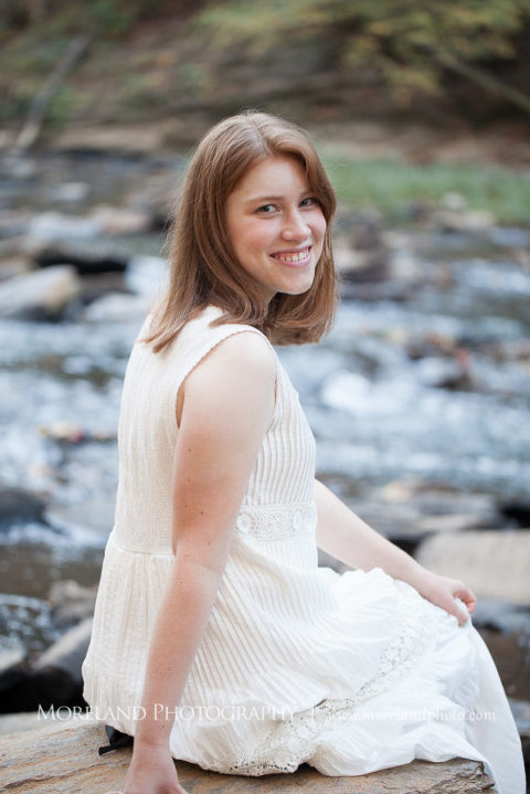 Georgia senior portraits of a girl sitting on a rock looking over her shoulder smiling, Mike Moreland, Moreland Photography, Atlanta Portrait Photographer, Senior Photography Atlanta, Kings Ridge Christian Academy, Nature, Georgia Senior Portrait, Outdoors Photography, Georgia Girl, Happy, Smile, White Dress, Rushing Water, Water, Nature 