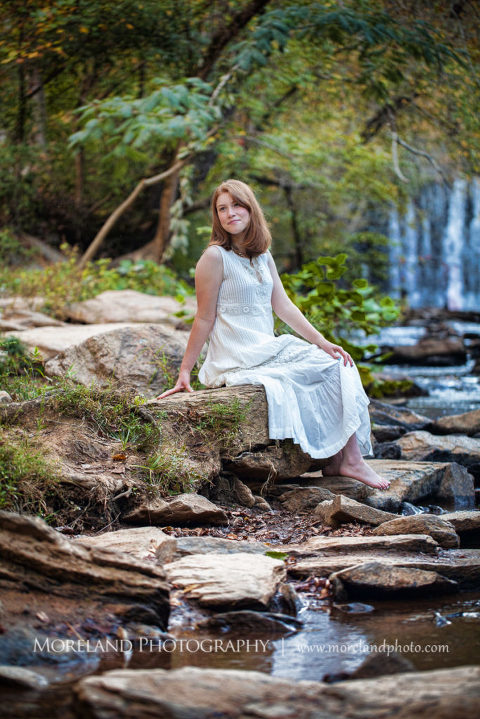 Georgia senior portraits of a girl sitting in a white dress in the rocks with a waterfall in the background, Mike Moreland, Moreland Photography, Atlanta Portrait Photographer, Senior Photography Atlanta, Kings Ridge Christian Academy, Nature, Georgia Senior Portrait, Outdoors Photography, Georgia Girl, White Dress, Smile, Girl, Waterfall, Trees, Water, Rocks, Nature