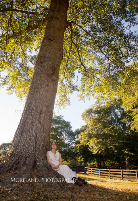 Georgia Senior portrait of a girl in nature sitting by a tall tree, Mike Moreland, Moreland Photography, Atlanta Portrait Photographer, Senior Photography Atlanta, Kings Ridge Christian Academy, Nature, Equestrian, Georgia Senior Portrait, Outdoors Photography, Georgia Girl, Tall Tree, Girl Sitting By Tree, Green, White Dress, Sitting Girl