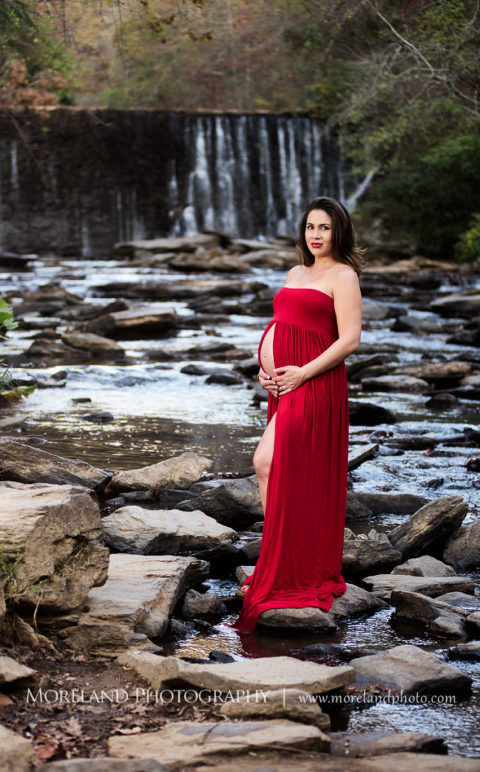 Maternity shoot of mother holding her belly wearing a red dress with waterfall in the background, Mike Moreland, Moreland Photography, Atlanta Portrait Photographer, Maternity Photography Atlanta, New Born Photography, New Born Photography Atlanta, Baby, Downtown Atlanta, Family, Mother, River Stream, Waterfall, Red Maternity Dress