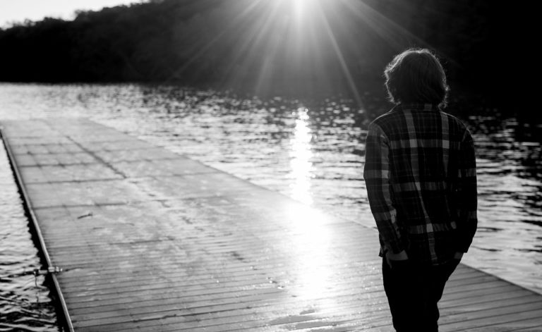 black and white image of boy walking toward the sun from a dock, moody black and white portrait, fine art portrait, Atlanta portrait photographer, Atlanta portrait photography