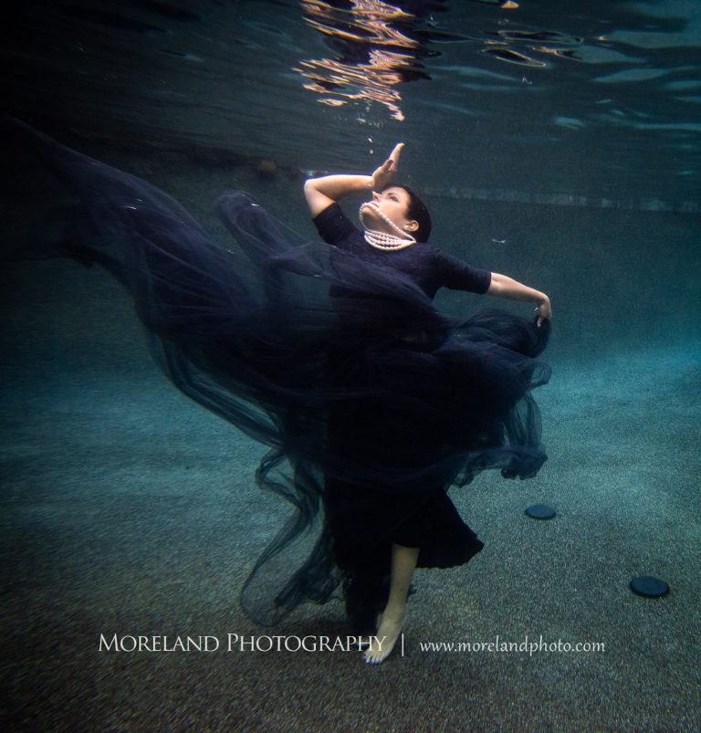 Woman in black dress underwater looking to the surface in deep thought, underwater portraits, creative photography atlanta, fashionable portrait ideas, moreland photography, celebration photo shoot, underwater photography, nikon, Georgia underwater photography