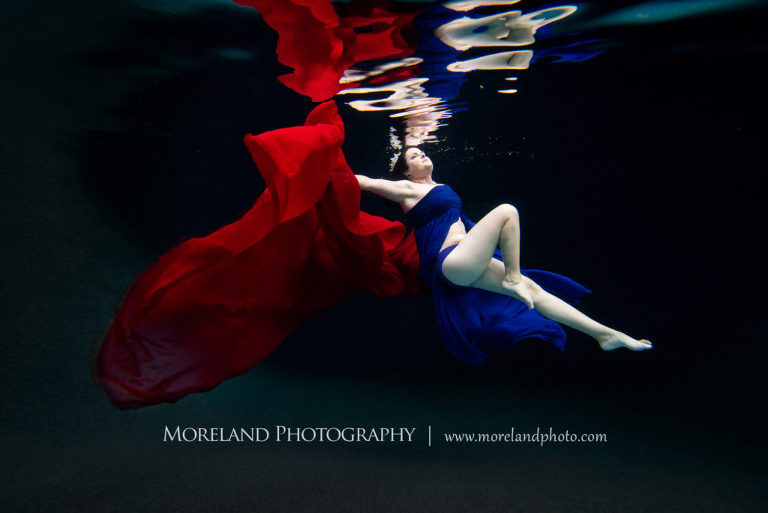 woman posing for underwater portrait with dark blue and red dress, underwater portraits, creative photography atlanta, creative edge workshops, moreland photography, florida underwater portraits, underwater photography, nikon, atlanta underwater photographer